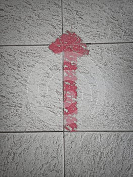 Faded arrow-shaped red duct tape on the floor