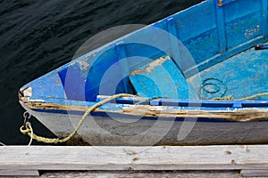 Faded blue wooden dinghy rowboat tied to dock