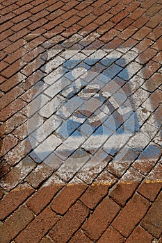 Faded handicapped parking sign on cobblestone bricks