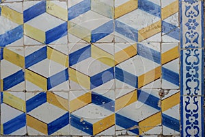 Faded wall with damaged vintage tiling in blue and yellow colours. Decadent facade in Evora, Portugal