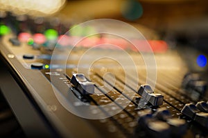 Faders pushed up on an audio console with blurred out background