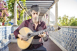 Fado musician playing on portuguese guitar under pergola in Lisbon, Portugal