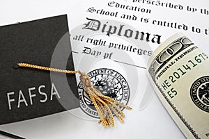 FAFSA Free Application for Federal Student Aid text on graduation cap with diploma and money