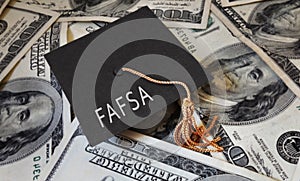 FAFSA Free Application for Federal Student Aid text on graduation cap and money - financial aid concept