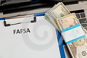 Fafsa. Student aid statement form and money on the tablet.