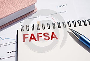 FAFSA text written on notepad with pen on financial documents