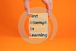 FAIL first attempt in learning symbol. Wooden blocks with words FAIL first attempt in learning. Beautiful orange table, orange