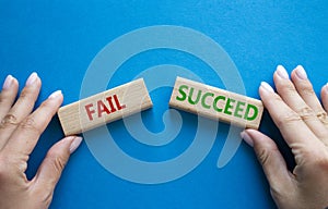 Fail or Succeed symbol. Concept word Fail or Succeed on wooden blocks. Businessman hand. Beautiful blue background. Business and