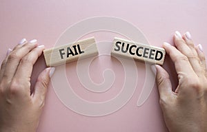 Fail or Succeed symbol. Concept word Fail or Succeed on wooden blocks. Businessman hand. Beautiful pink background. Business and