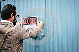 Failed business man store owner with closed signs on the door of his shop - coronavirus lockdown economy emergency crisis concept