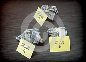 Failed business plan A, B and C, minted dollar banknotes on a wooden desk photo
