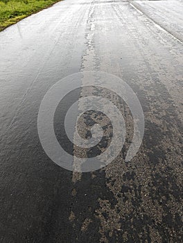 Failing road surface in Wales, showing deterioration, construction site, rain-wetted tarmac