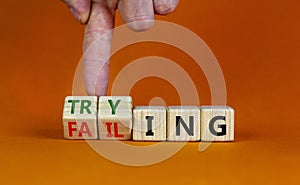 Failing or trying symbol. Businessman turns wooden cubes and changes the word `failing` to `trying`. Beautiful orange backgrou