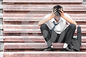 Failure unemployed stressed young asian business man covering head with hands. A young businessman sitting desperate on the stairs