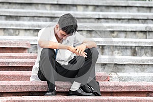 Failure unemployed stressed young asian business man. A young businessman sitting desperate on the stairs because low economic