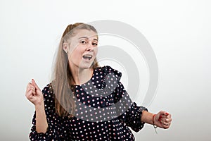 Fair-haired girl in a black dress with white circles dances waving her arms