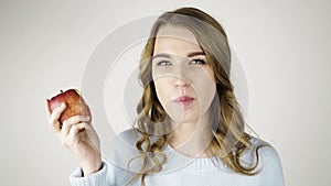 Fair haired woman biting a red apple and flirting