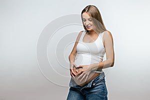 Fair-haired young pregnant woman holding her big belly