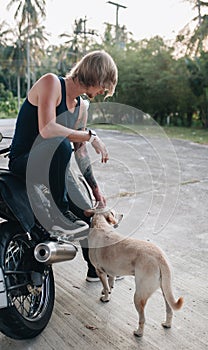 Fair man is sitting on his motorbike with a dog