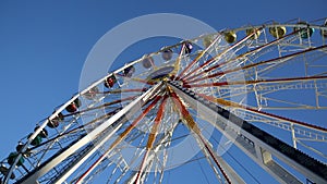 Fairground, Ferris wheel close-up in front of blue sky. the Ferris wheel is turning around