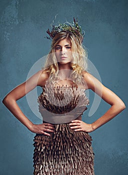 Fairy fashion. a young woman posing with flowers in her hair against a blue background.