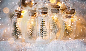 Fairy lights in a jar with a Christmas tree and snow close-up on a warm cozy mood with golden garland. Christmas and New Year,