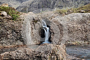 Fairy Pools waterfall cascades into a tranquil pool, framed by Isle of Skye rugged cliffs