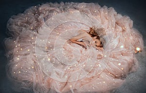 Fairy queen fashion model in luxurious shining pink dress posing in studio. Princess girl, peach outfit with sequins