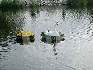 Fairy swan of flowers floating on a wreath on a lake