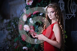 Fairy tale. Beautiful princess in red dress sitting in a mystical garden