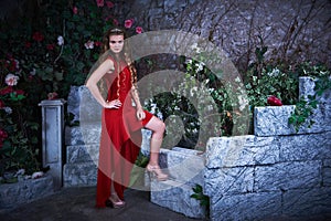 Fairy tale. Beautiful princess in red dress sitting in a mystical garden