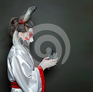 Fairy tale character. Woman hare holding pigeon bird on black background. Halloween makeup costume