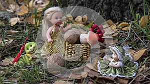 Fairy-tale  composition  of beautiful princesses with straw box filled nuts and mushrooms, and  funny caterpillar in the forest.