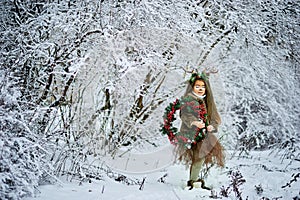 Fairy tale girl. Portrait a little girl in a deer dress with a painted face in the winter forest. Big brown antler