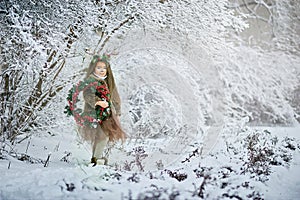 Fairy tale girl. Portrait a little girl in a deer dress with a painted face in the winter forest. Big brown antler