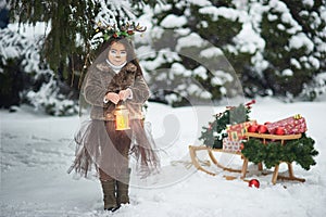 Fairy tale girl. Portrait a little girl in a deer dress with a painted face in the winter forest. Big brown antler