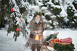 Fairy tale girl. Portrait a little girl in a deer dress with a painted face in the winter forest. Big brown antler