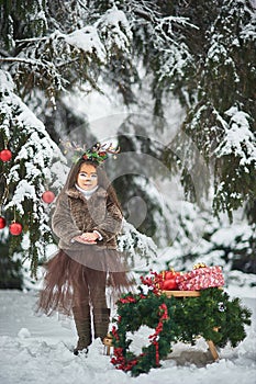 Fairy tale girl. Portrait a little girl in a deer dress with a painted face in the winter forest. Big brown antler