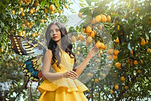 fairy tale girl walking in fabulous lemon garden. Fantasy woman in bright yellow dress pixie costume, fake plastic