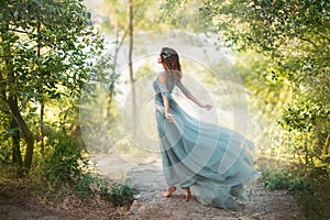 Fairy-tale princess in light summer blue turquoise dress on wide path photo