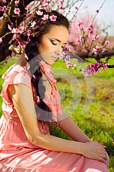 Fairy young woman sitting in blossomy garden