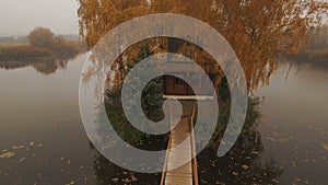 Fairytale house in the middle of the lake on an autumn foggy morning aerial