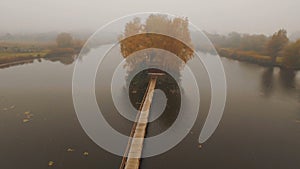 Fairytale house in the middle of the lake on an autumn foggy morning aerial