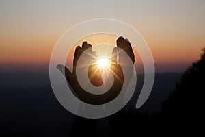 Spiritual prayer hands over sun shine with blurred beautiful sunset background