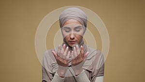 Faith concept. Studio portrait of young peaceful middle eastern muslim lady wearing traditional hijab praying to God