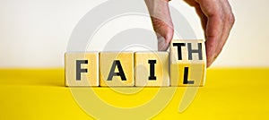 Faith instead fail symbol. Businessman turns a wooden cube and changes the word fail to faith. Beautiful yellow table, white