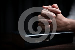 Faith with holy bible concept. Hands of a female prayer worship God with holy bible on black background in church. Christian woman