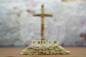 Faith letters with defocus holy cross on leather table and concrete wall background.