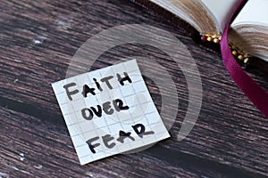 Faith over fear, handwritten text with open holy bible book on wood