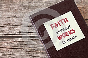 Faith without works is dead, a handwritten quote on a note on top of a closed Christian Holy Bible Book photo